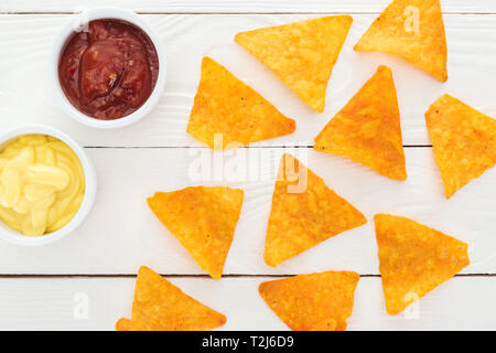top view of tasty nachos and sauces on white wooden table Stock Photo