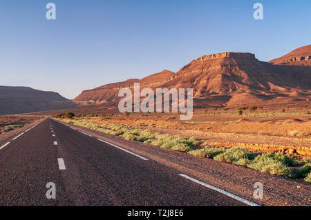 Straight highway in beautiful moroccan landscape with mountains in the sunset Stock Photo