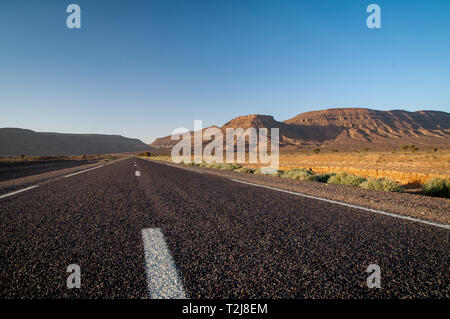 Straight highway in beautiful moroccan landscape with mountains in the sunset Stock Photo