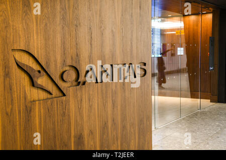 LONDON HEATHROW AIRPORT, ENGLAND - FEBRUARY 2019:  Qantas sign in the wooden panel outside its business lounge in Terminal 3 at London Heathrow Stock Photo