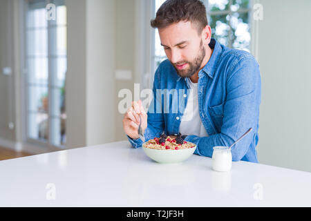 Handsome man having breakfast eating cereals at home and smiling Stock Photo