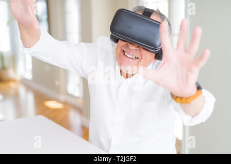 Man wearing virtual reality glasses smiling looking very happy and excited Stock Photo