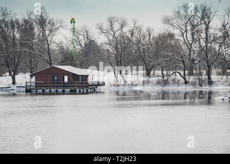 Two fishermen on a covered fishing dock on a lake in Sedgwick county park in Wichita, Kansas, USA after a late winter snowfall. Stock Photo