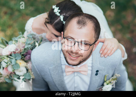 Bride and groom on wedding day, hugging, stand near the cliff and look up. Stock Photo