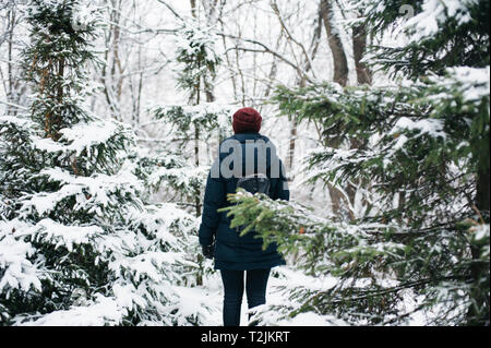Rear view of young woman walking in winter forest