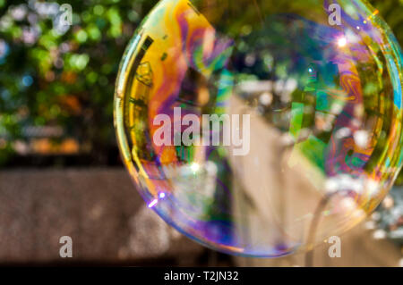 kids big rainbow colored soap bubble floating in garden Stock Photo