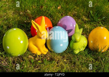 Colorful ceramic easter eggs and Easter bunnies on a meadow. Stock Photo