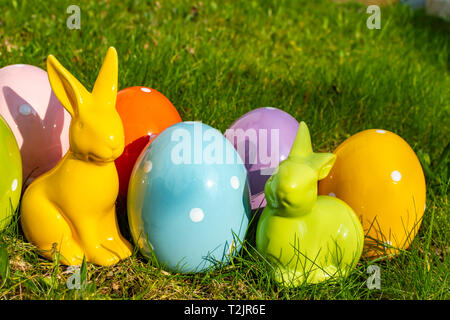 Colorful ceramic easter eggs and Easter bunnies on a meadow. Stock Photo