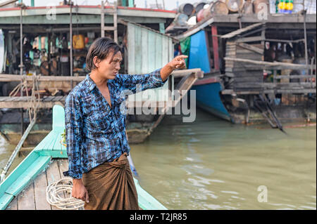 Boatman piloting a tourist vessel on the Irrawaddy River, Mingun Jetty, Mandalay, Myanmar (Burma) Stock Photo