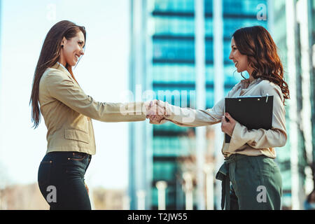 Two businesswomen shaking hands with each other after good deal. Stock Photo