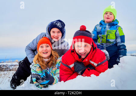 Portrait of a family with four people having fun in the snow. Dad, mom and two sons in winter day outdoor Stock Photo