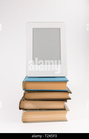 Electronic book on the top of the stack of regular old books isolated on white background Stock Photo