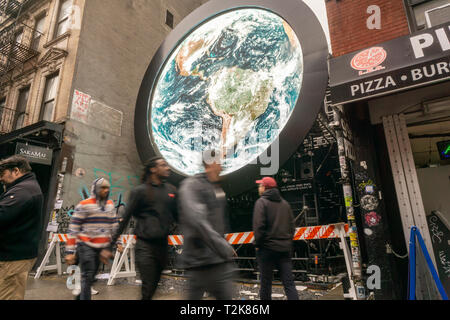 Visitors pass a livestream view of the planet Earth taken from a  NASA satellite is projected on an installation entitled 'blu Marble' on Ludlow Street in the Lower East Side neighborhood of New York on Sunday, March 31, 2019. The work by artist Sebastian Errazuriz is sponsored by the vaping company blu as part of their charitable 'Pledge World by blu' campaign. (Â© Richard B. Levine) Stock Photo