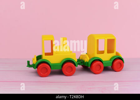 children's toy train for playing with cars yellow on a pink background Stock Photo