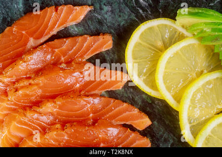 Delicious healthy homemade salmon slices of avocado and slices of lemon board ready to eat Stock Photo
