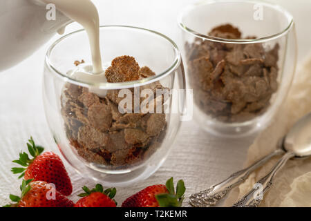 Toasted Bran Flakes Cereal with Yogurt and Fresh Strawberries in a Glass Cups on a Kitchen Table in White Background Stock Photo
