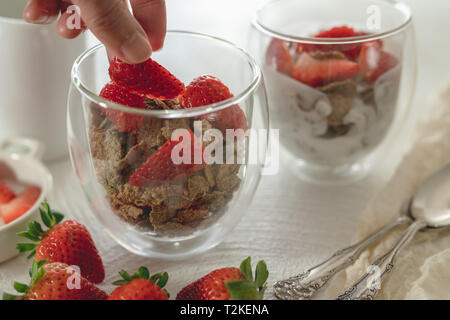 Toasted Bran Flakes Cereal with Yogurt and Fresh Strawberries in a Glass Cups on a Kitchen Table in White Background Stock Photo