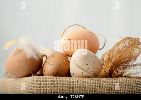 Rustic easter eggs in a jute basket on a white background Stock Photo