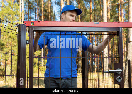 man check the level of new fence gates Stock Photo