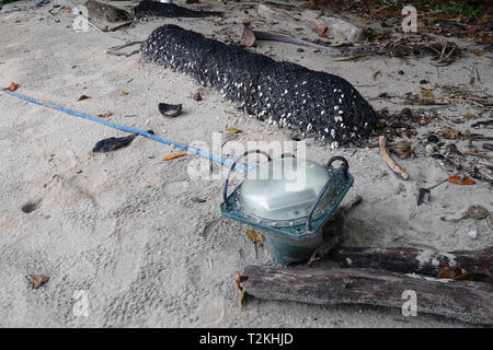 Lost fishing gear and a ghost net that has been neatly rolled up and ready to be removed from the beach, Etty Bay, Queensland, Australia. No PR Stock Photo