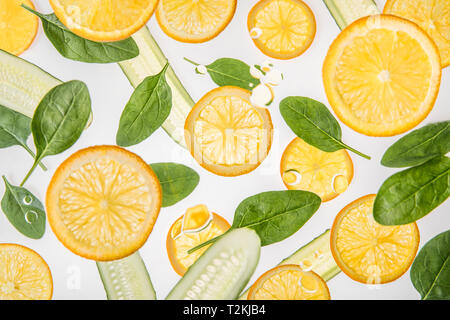 orange slices with green spinach leaves and cucumbers on grey background Stock Photo