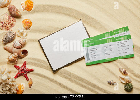top view of blank placard near air tickets and seashells on sand Stock Photo