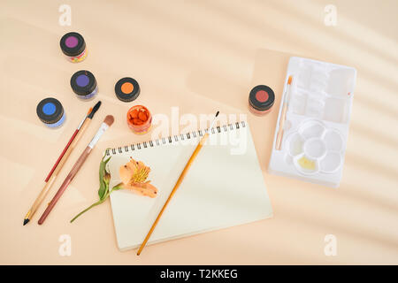 Set of watercolor paint, art brushes and paper on a desk Stock Photo