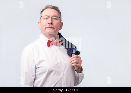 Confident senior businessman in blue suit and red bow tie. Serious boss at studio. Stock Photo