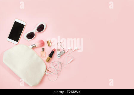 Top view female accessories: cosmetics makeup, sunglasses, mobile phone, headphones flash drive on pastel pink background. Valentine's Day, 8 March, b Stock Photo