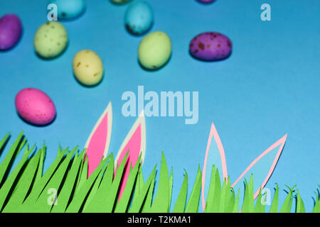 Grass With Rabbit Ears And Candy Eggs On Blue Stock Photo