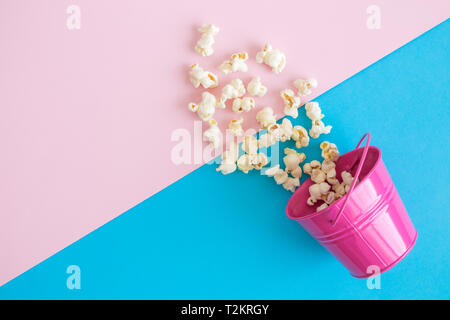 Flat lay of small metal bucket with spilled popcorn on pastel background minimal creative concept. Stock Photo