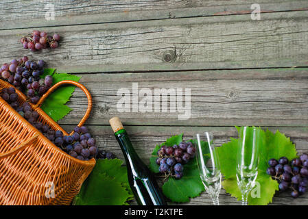Wine bottles with grapes, basket, two wineglasses on wooden background Stock Photo