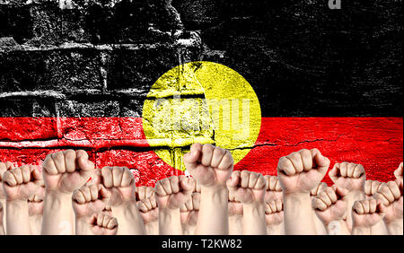 Male hands clenched in a fist raised up against the backdrop of a destroyed brick wall with a flag of Australian Aboriginal. The concept of the labor  Stock Photo