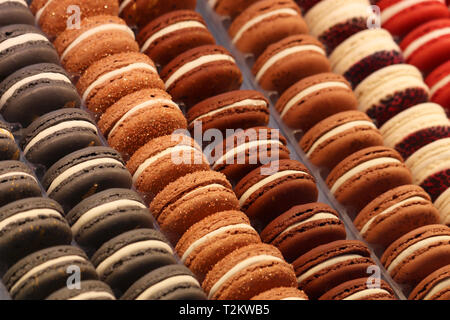 Colorful macaroons close-up. Almond cookies with chocolate and berry filling in a row, sweet background Stock Photo