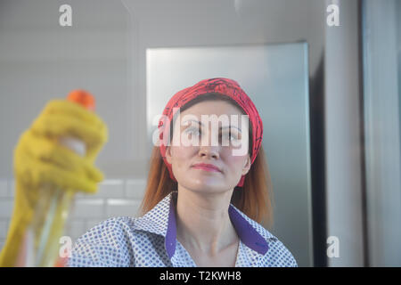 Woman Doing Housework. Housewife Portrait While Cleaning. Photo Through the Glass. Woman cleaning the window with spray. Spring cleaning Stock Photo