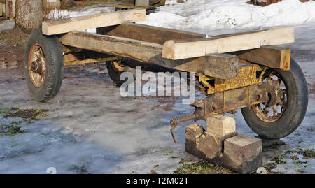 Repair of an old horse cart in the courtyard of a village house. Sunny winter day rural landscape Stock Photo