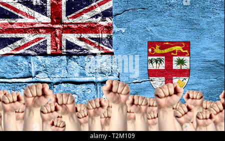 Male hands clenched in a fist raised up against the backdrop of a destroyed brick wall with a flag of Fiji. The concept of the labor movement from the Stock Photo