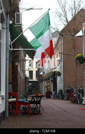 ARNHEM, NETHERLANDS - MARCH 22, 2019: Ancient street in the center of Arnhem with Italian flags, terrace and bicycles: Bentinckstraat Stock Photo