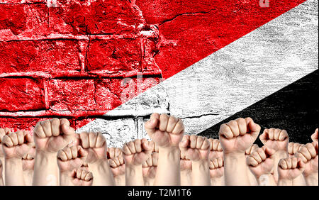 Male hands clenched in a fist raised up against the backdrop of a destroyed brick wall with a flag of Sealand,Principality of. The concept of the labo Stock Photo