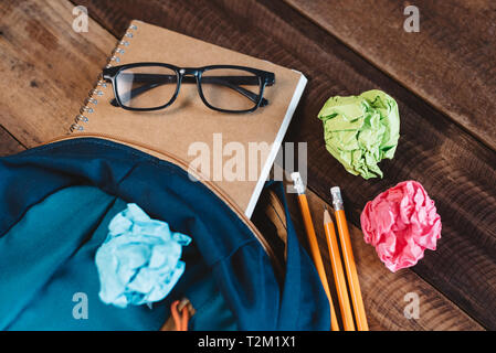 School bag,eyeglasses,pencil,notebook and colorful wrapped paper on a wooden table. concept of school equipment, preparation and education Stock Photo