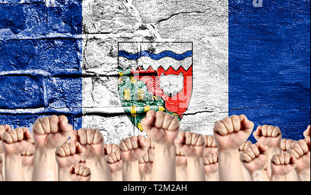 Male hands clenched in a fist raised up against the backdrop of a destroyed brick wall with a flag of Northwest Territories. The concept of the labor  Stock Photo
