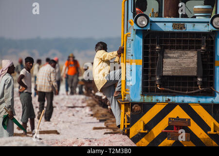 SAMBHAR, INDIA - NOVEMBER 19, 2012: Indian male climb on the locomotive at salt mine at lake Sambhar, Rajasthan, India. Stock Photo