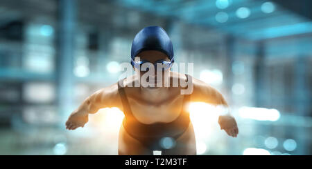 Swimmer standing on diving board ready to jump into swimming pool. Mixed media Stock Photo