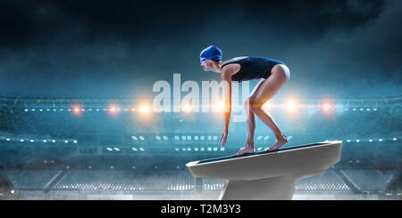 Swimmer standing on diving board ready to jump into swimming pool. Mixed media Stock Photo