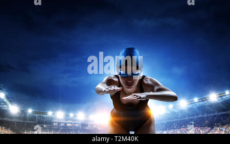 Swimmer standing on diving board ready to jump into swimming pool. Mixed media Stock Photo