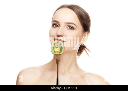 Beautiful smiling girl with clean and healthy skin with kiwi near lips. Cosmetology , treatment, beauty and spa . Skin care and aromatherapy. Stock Photo