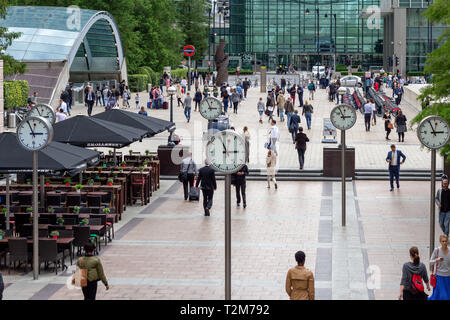 LONDON, ENGLAND - AUGUST 27 2015: Commuters walking through Reuters Plaza, Canary Wharf, London past the 'Six Public Clocks' by Konstantin Grcic Stock Photo