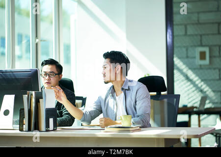 two young asian business people working together in office discussing business.