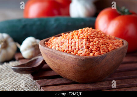 Raw uncooked red lentils (lens culinaris) in wooden bowl Stock Photo