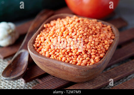 Raw uncooked red lentils (lens culinaris) in wooden bowl Stock Photo